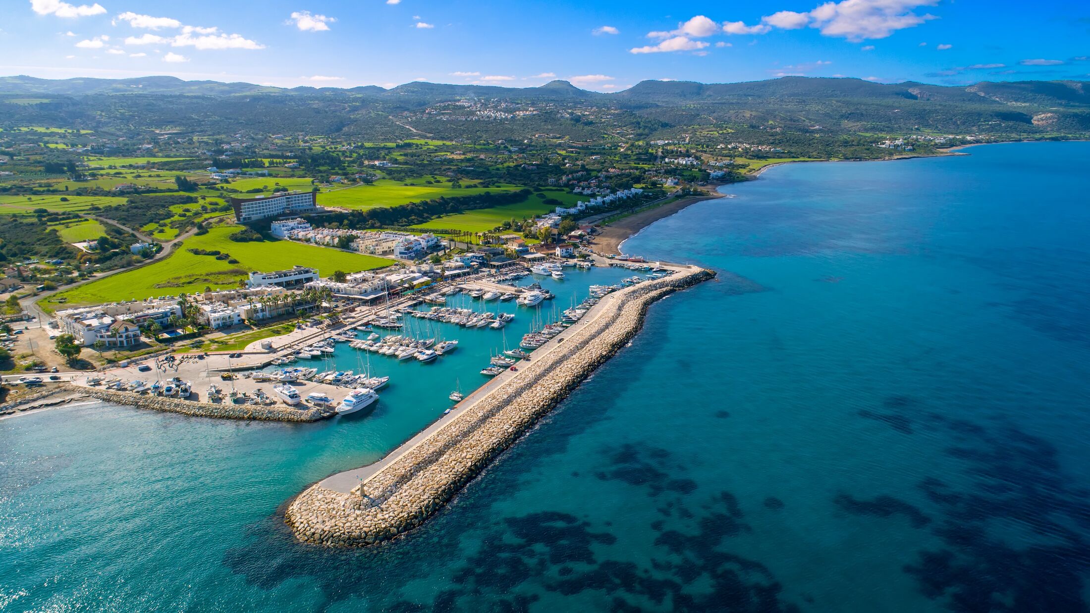 Aerial bird's eye view of Latchi port, Akamas peninsula, Polis Chrysochous, Paphos,Cyprus. Latsi harbour with boats and yachts, fish restaurant, promenade, beach tourist area and mountains from above