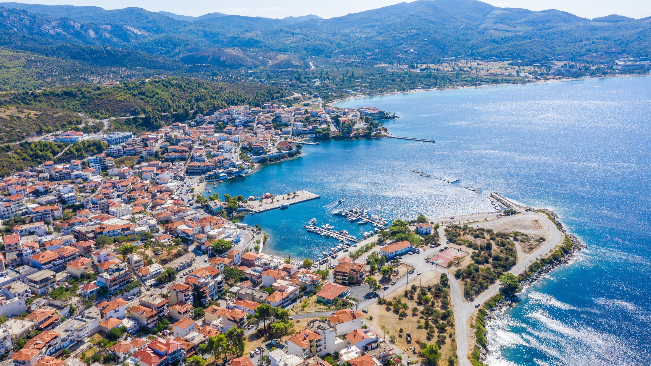 Aerial sunset view of amazing Neos Marmaras cityscape and distant turtle island in Greece.